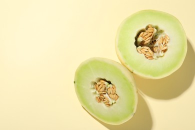 Photo of Cut fresh ripe honeydew melon on beige background, top view. Space for text