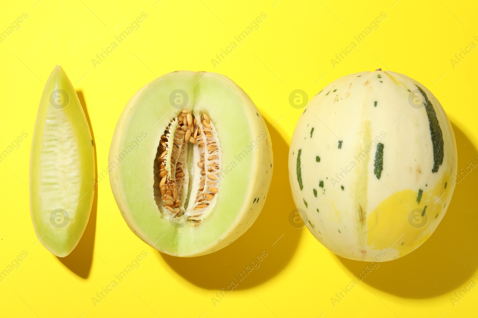 Photo of Fresh ripe honeydew melons on yellow background, top view