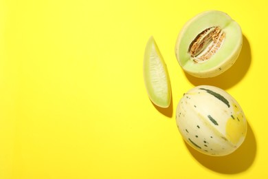 Photo of Fresh ripe honeydew melons on yellow background, top view. Space for text