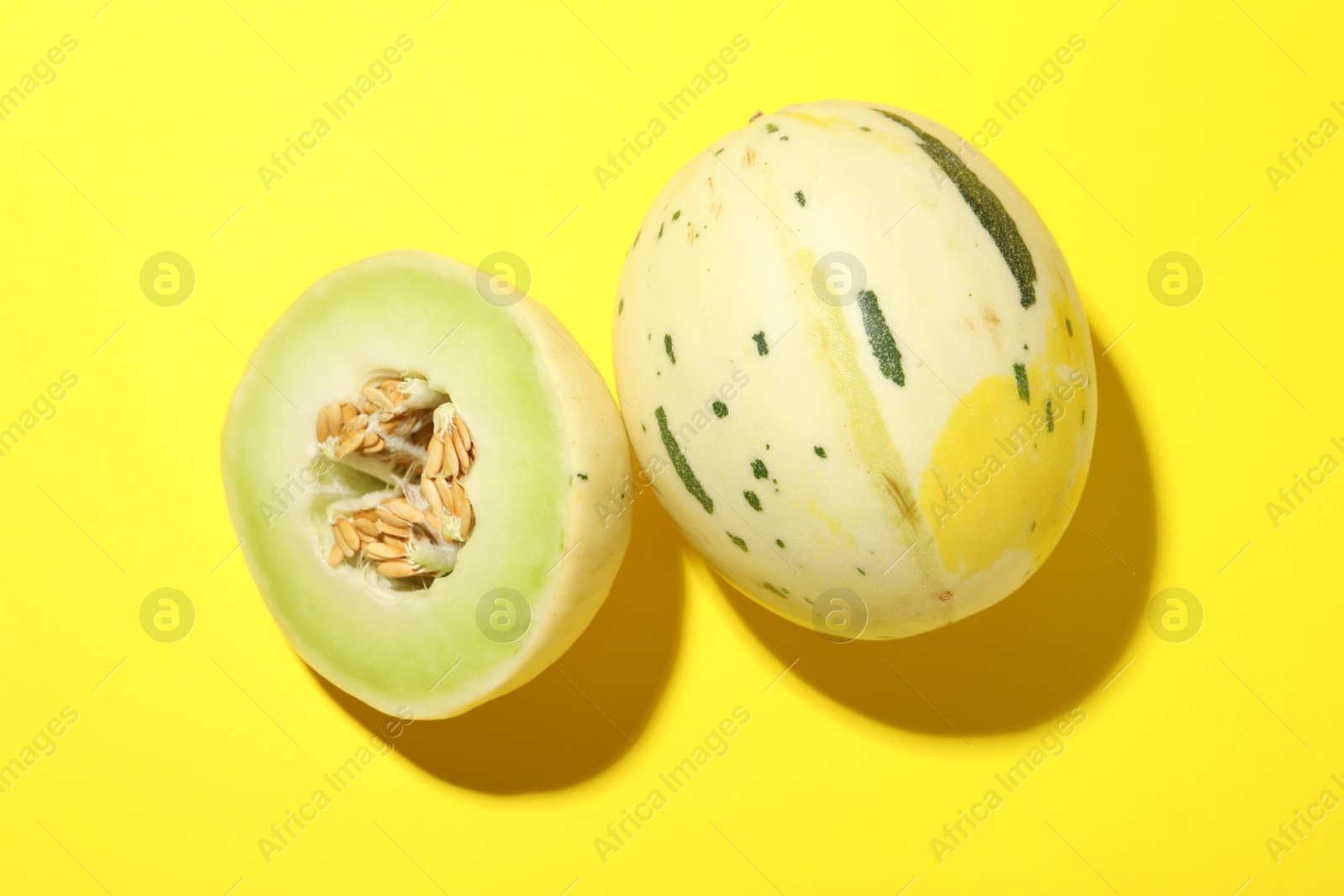 Photo of Fresh ripe honeydew melons on yellow background, top view