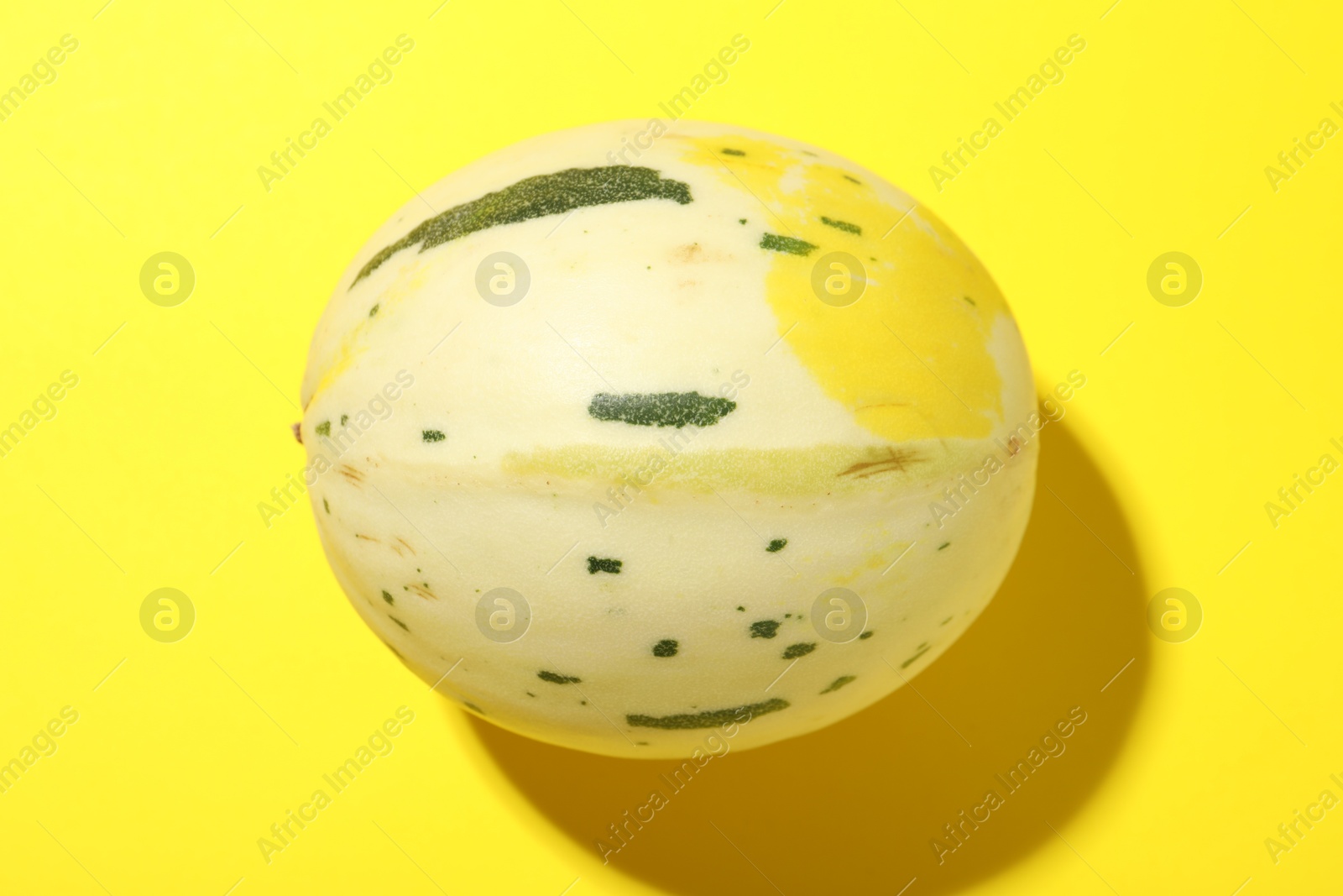 Photo of Fresh ripe honeydew melon on yellow background, top view