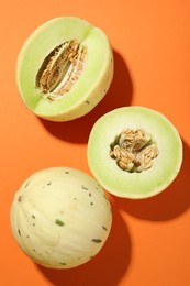 Photo of Fresh ripe honeydew melons on orange background, top view