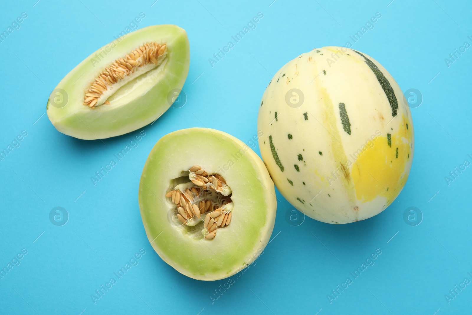 Photo of Fresh ripe honeydew melons on light blue background, top view