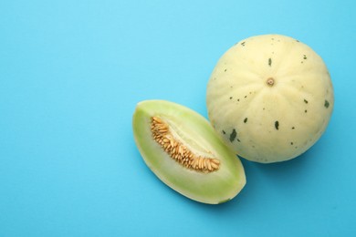 Photo of Fresh ripe honeydew melons on light blue background, top view. Space for text