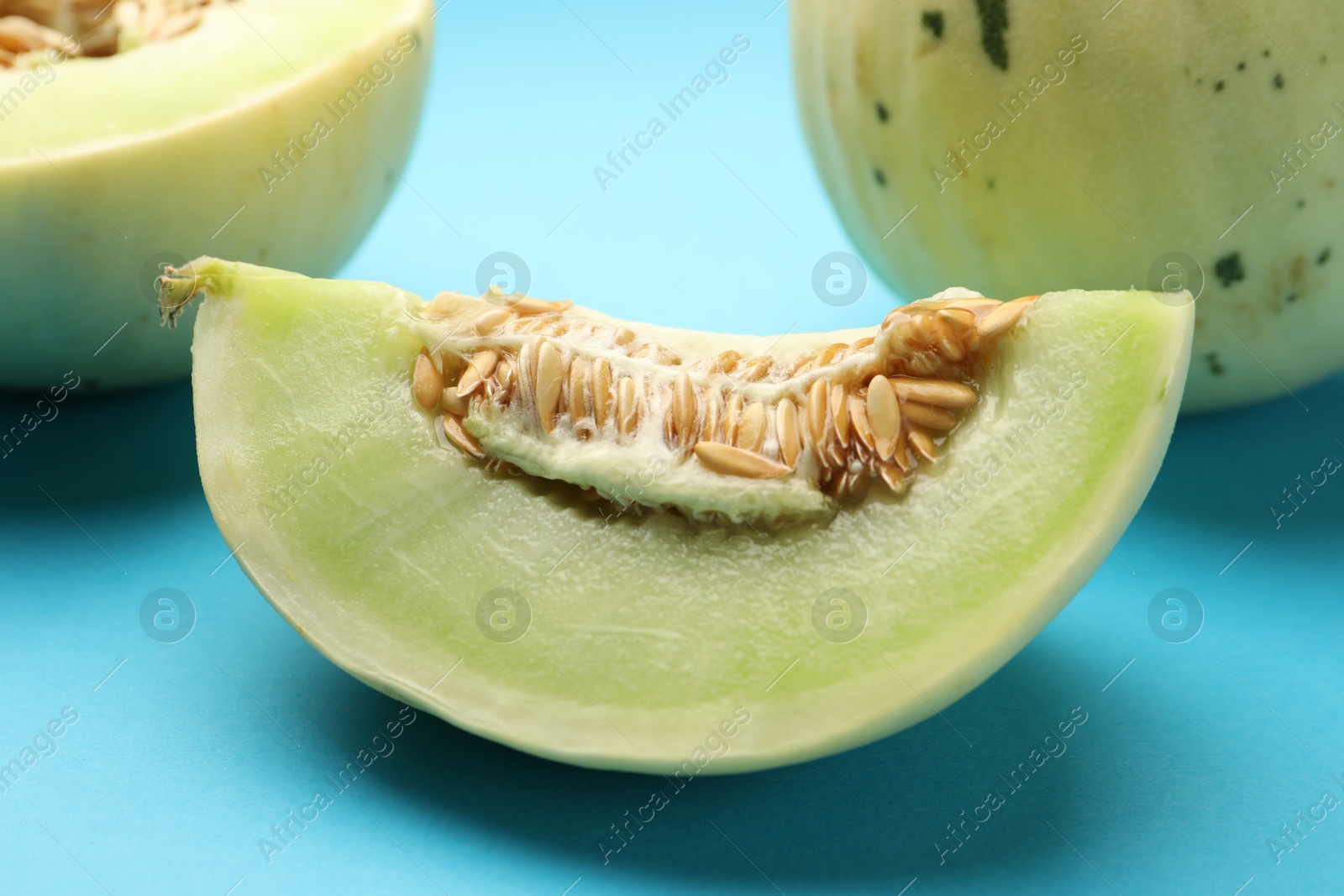 Photo of Cut fresh ripe honeydew melon on light blue background, closeup