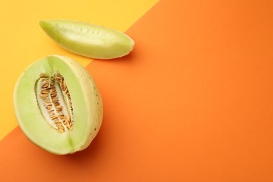 Photo of Cut fresh ripe honeydew melon on color background, top view. Space for text