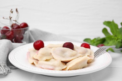 Photo of Traditional Ukrainian dumplings (varenyky) with cherries served on white tiled table, closeup