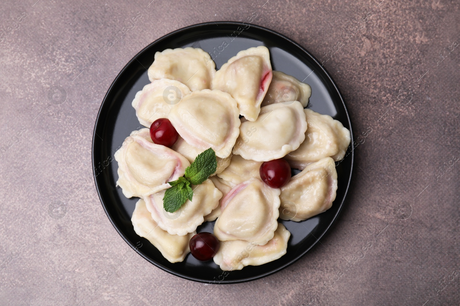 Photo of Traditional Ukrainian dumplings (varenyky) with cherries on brown table, top view