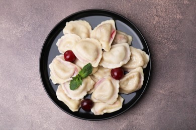 Photo of Traditional Ukrainian dumplings (varenyky) with cherries on brown table, top view