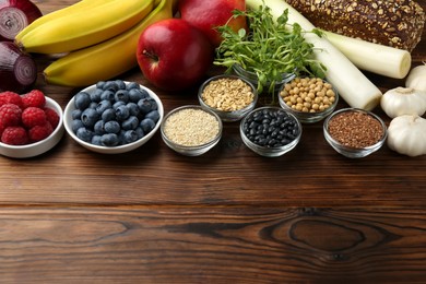 Photo of Different fresh products on wooden table, space for text. Source of prebiotics