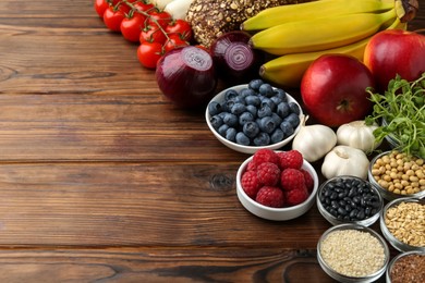 Photo of Different fresh products on wooden table, space for text. Source of prebiotics