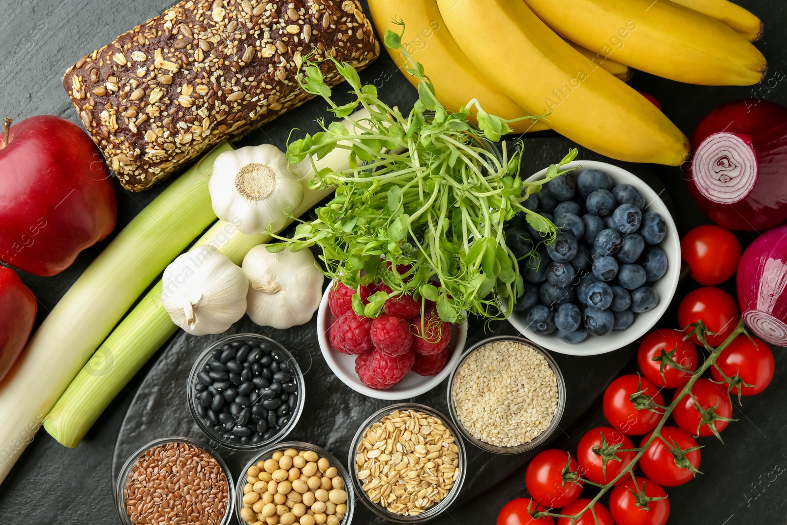 Photo of Different fresh products on black table, flat lay. Source of prebiotics