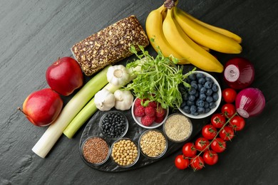 Photo of Different fresh products on black table, flat lay. Source of prebiotics