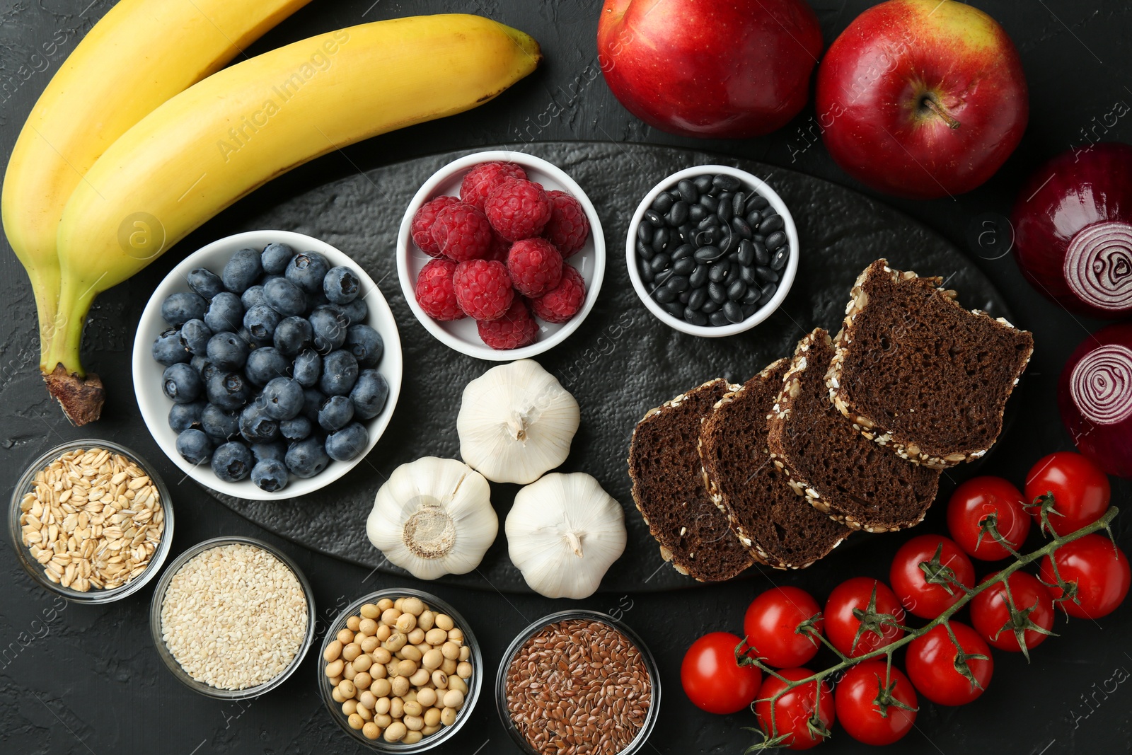 Photo of Different fresh products on black table, flat lay. Source of prebiotics