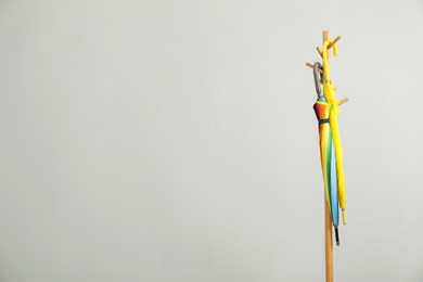 Photo of Colorful umbrellas on clothing rack against light grey background, space for text