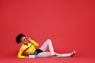 Photo of Aerobics. Woman in sportswear holding radio receiver on red background