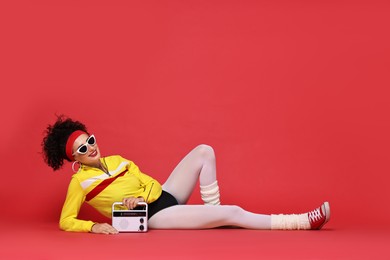 Aerobics. Woman in sportswear holding radio receiver on red background