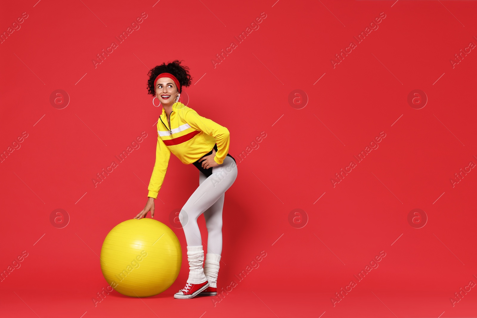 Photo of Aerobics. Happy woman with fitness ball on red background