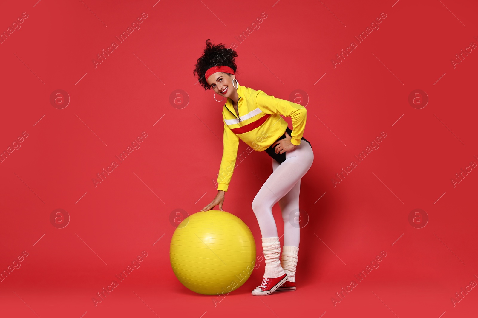 Photo of Aerobics. Happy woman with fitness ball on red background