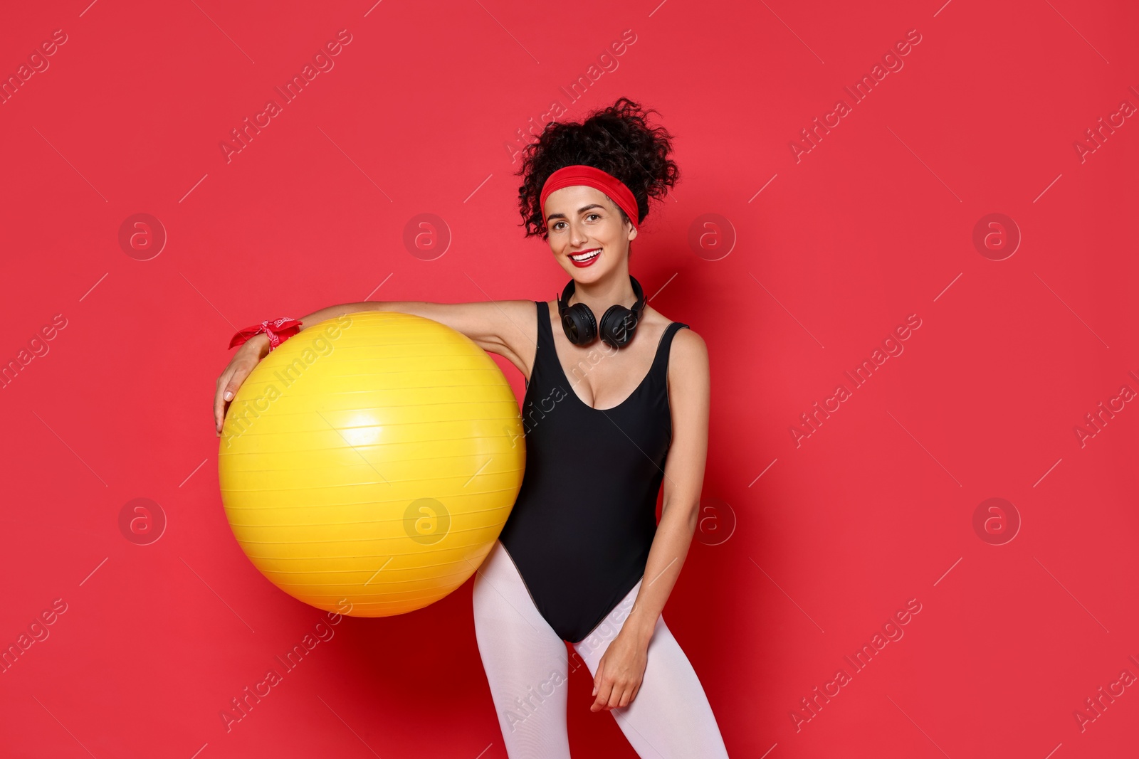 Photo of Aerobics. Happy woman with fitness ball on red background