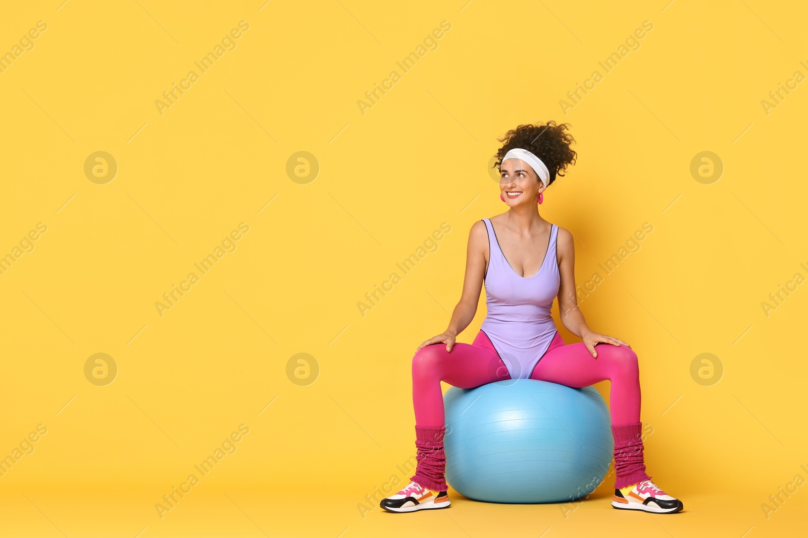 Photo of Aerobics. Woman with fitness ball on orange background, space for text