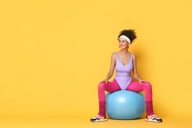 Aerobics. Woman with fitness ball on orange background, space for text