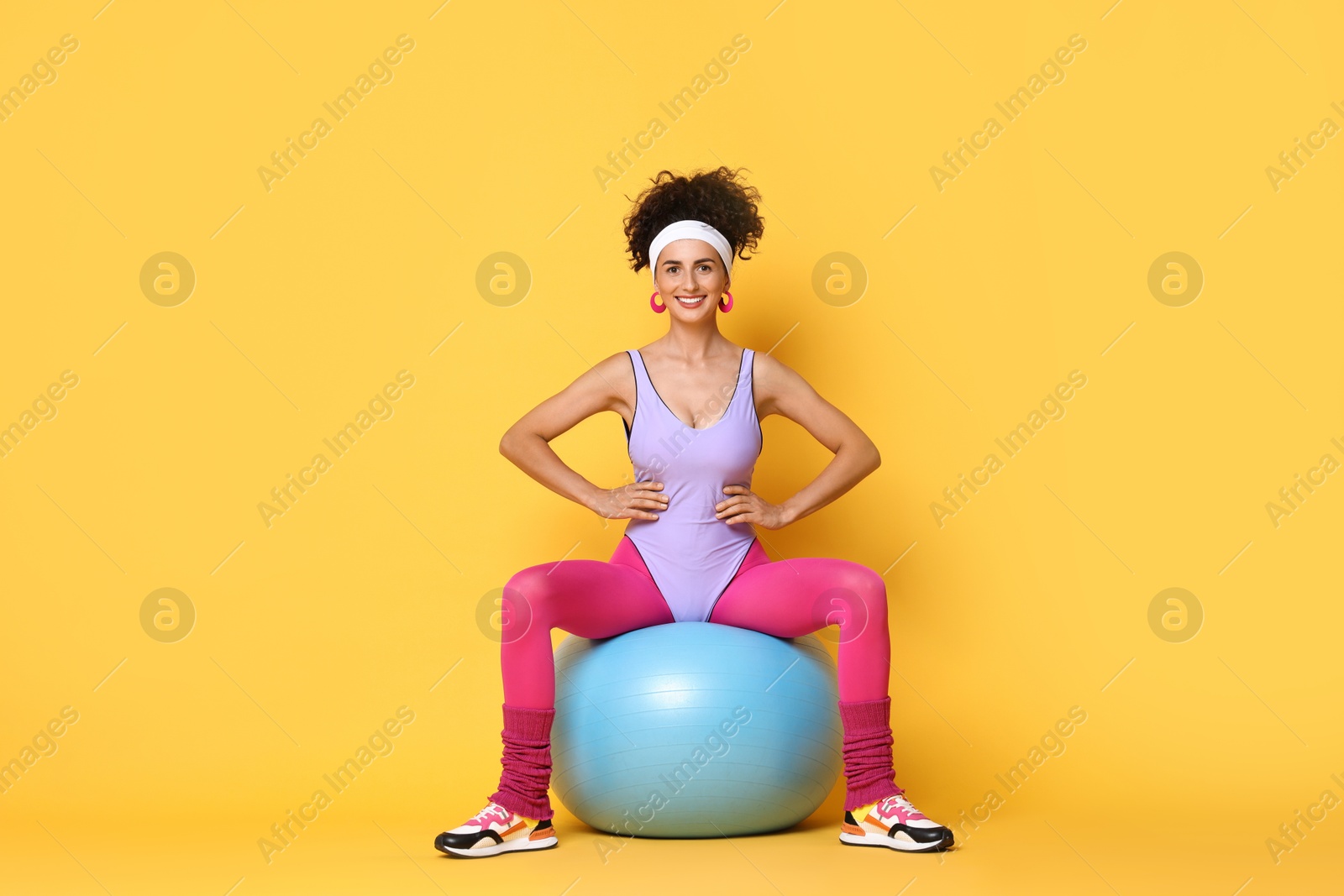 Photo of Aerobics. Woman with fitness ball on orange background