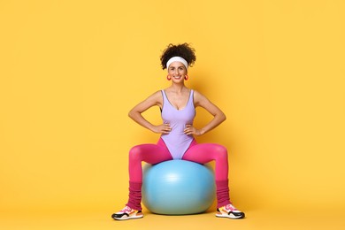 Photo of Aerobics. Woman with fitness ball on orange background