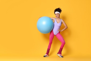 Photo of Aerobics. Woman with fitness ball on orange background