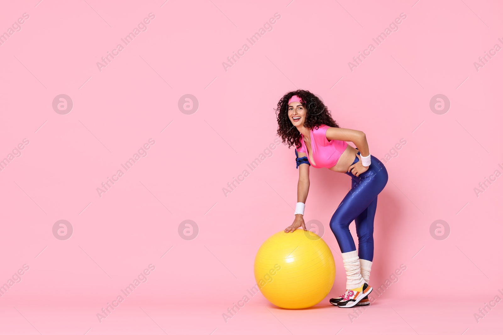 Photo of Aerobics. Happy woman with fitness ball on pink background, space for text