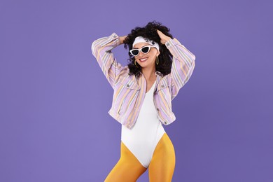 Aerobics. Happy woman in sunglasses on purple background