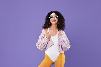 Aerobics. Happy woman in sunglasses on purple background