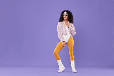 Aerobics. Happy woman in sunglasses on purple background, space for text