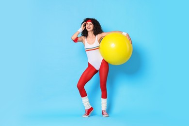 Aerobics. Happy woman with fitness ball on light blue background