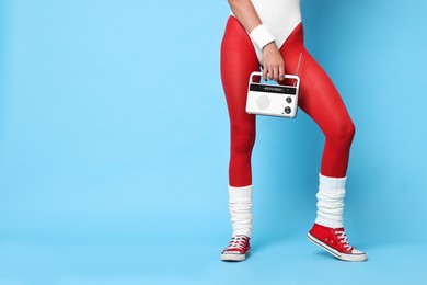 Aerobics. Woman with radio receiver on light blue background, closeup. Space for text