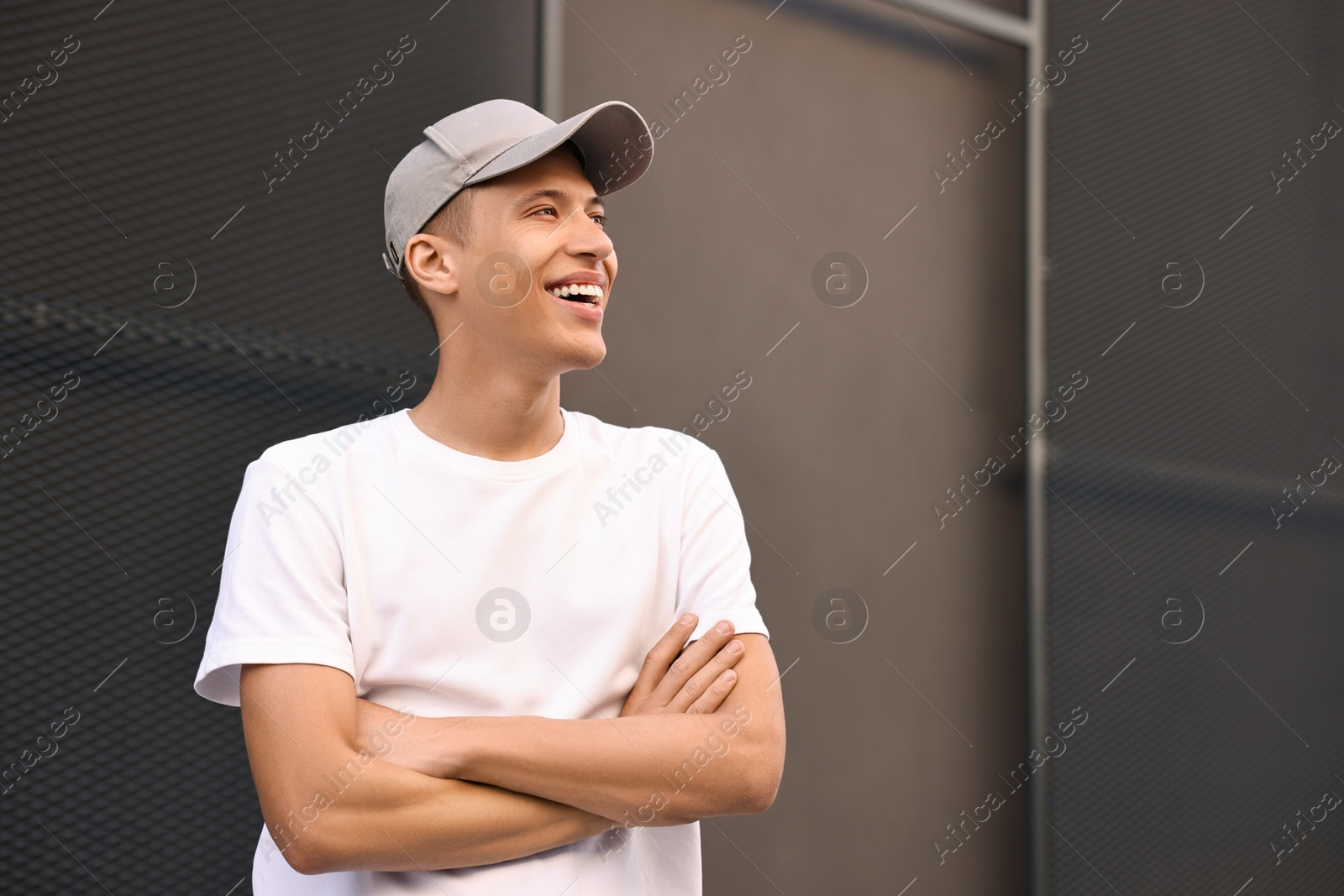 Photo of Smiling man in baseball cap near dark wall. Space for text