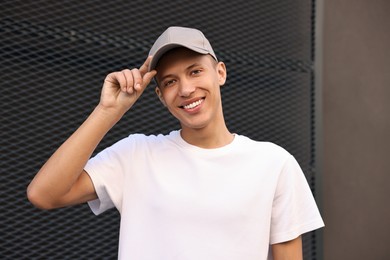 Portrait of smiling man in baseball cap near dark wall