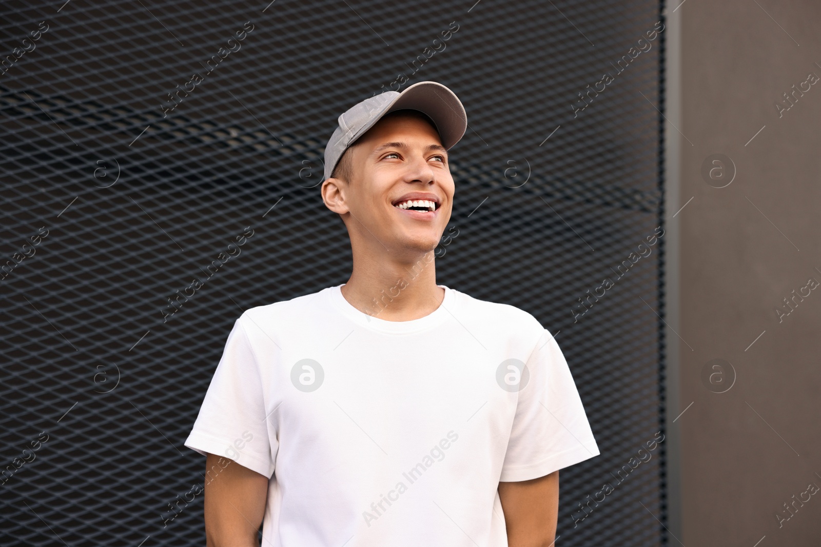 Photo of Portrait of smiling man in baseball cap near dark wall