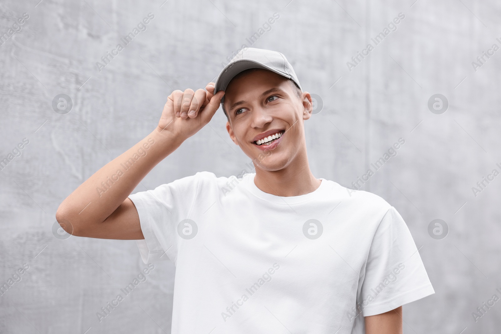 Photo of Portrait of smiling man in baseball cap near light wall