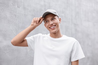 Portrait of smiling man in baseball cap near light wall