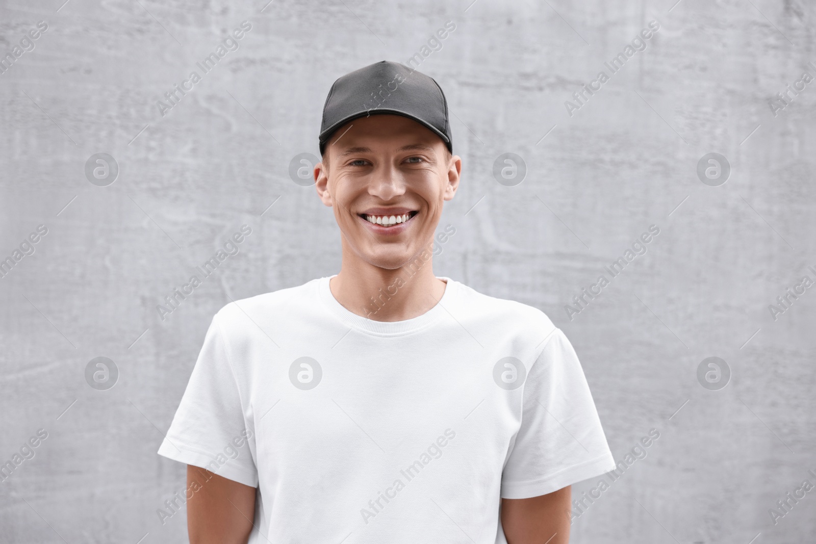 Photo of Portrait of smiling man in baseball cap near light wall