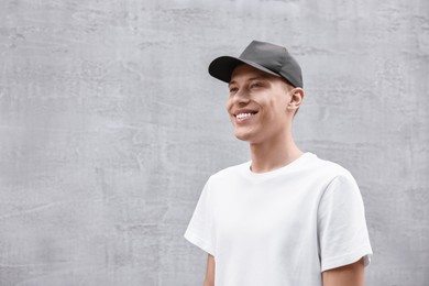 Portrait of smiling man in baseball cap near light wall. Space for text