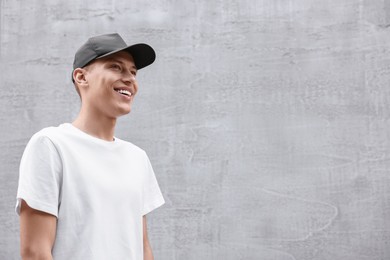 Photo of Portrait of smiling man in baseball cap near light wall. Space for text