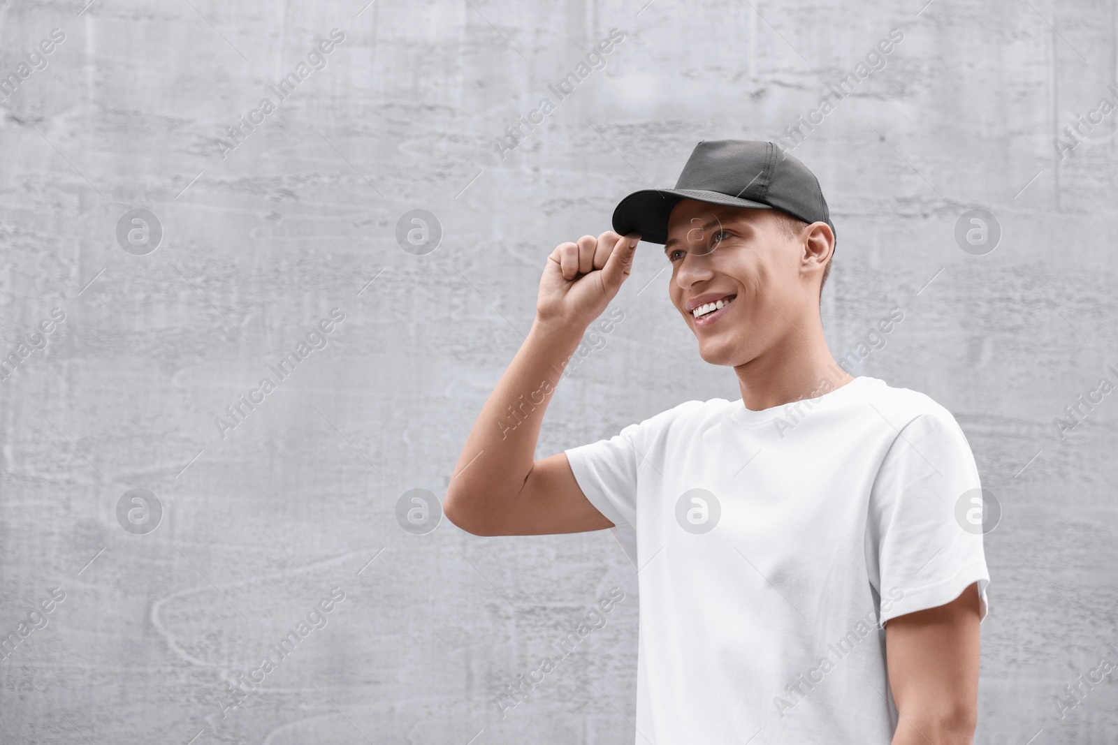 Photo of Portrait of smiling man in baseball cap near light wall. Space for text