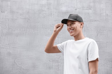 Portrait of smiling man in baseball cap near light wall. Space for text