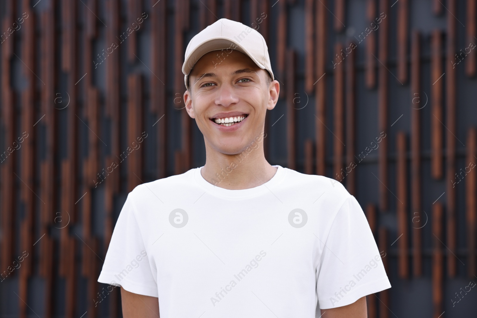 Photo of Portrait of smiling man in baseball cap near dark wall