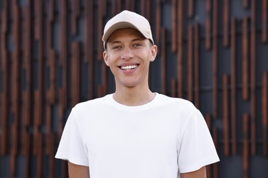 Portrait of smiling man in baseball cap near dark wall