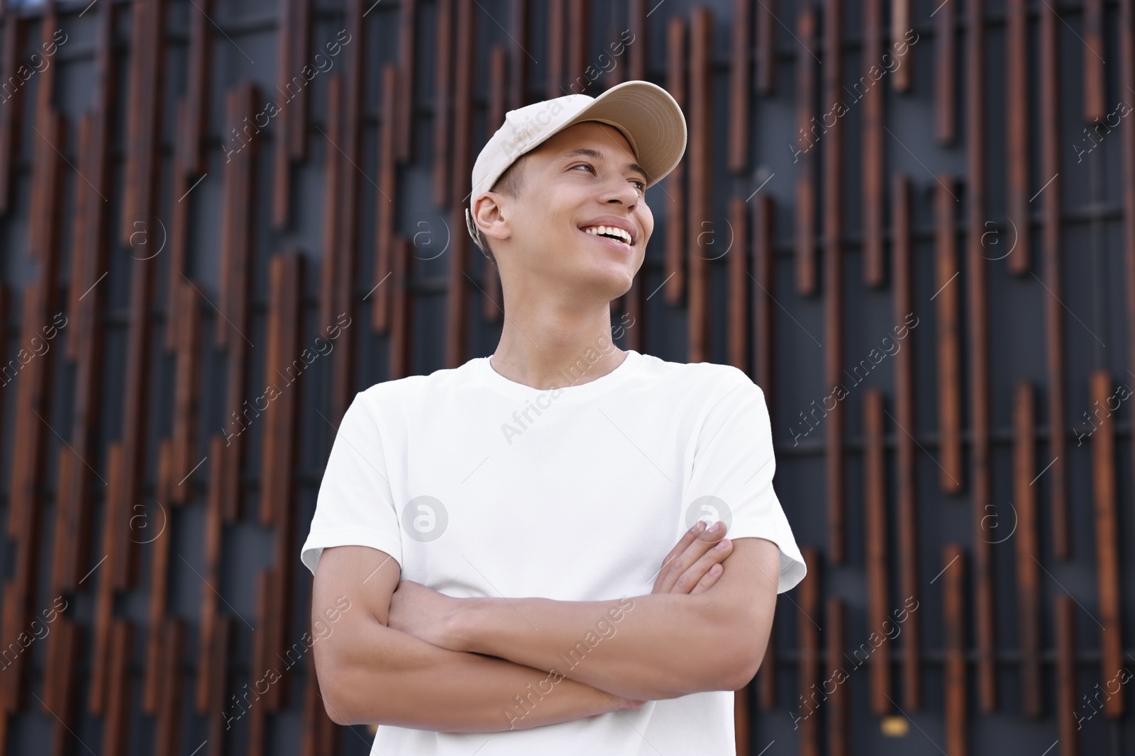 Photo of Portrait of smiling man in baseball cap near dark wall, low angle view