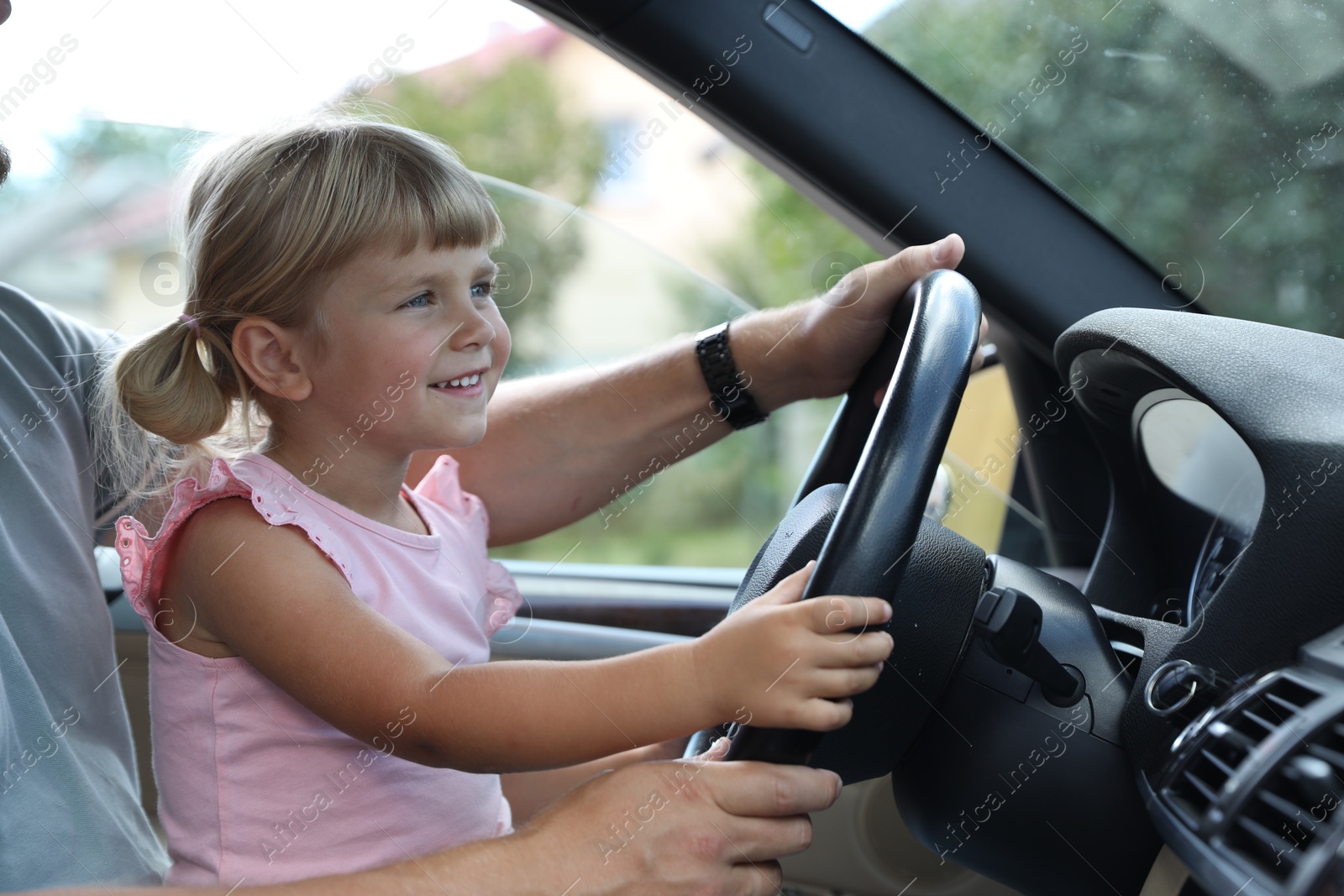 Photo of Man with his daughter holding steering wheel inside car, closeup