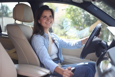 Smiling woman holding steering wheel while driving car